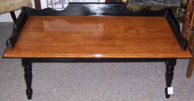 stained maple coffee table with black painted legs and decorative trim on table top