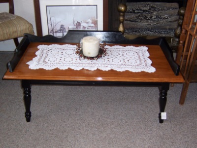stained maple coffee table with a doily and candle
