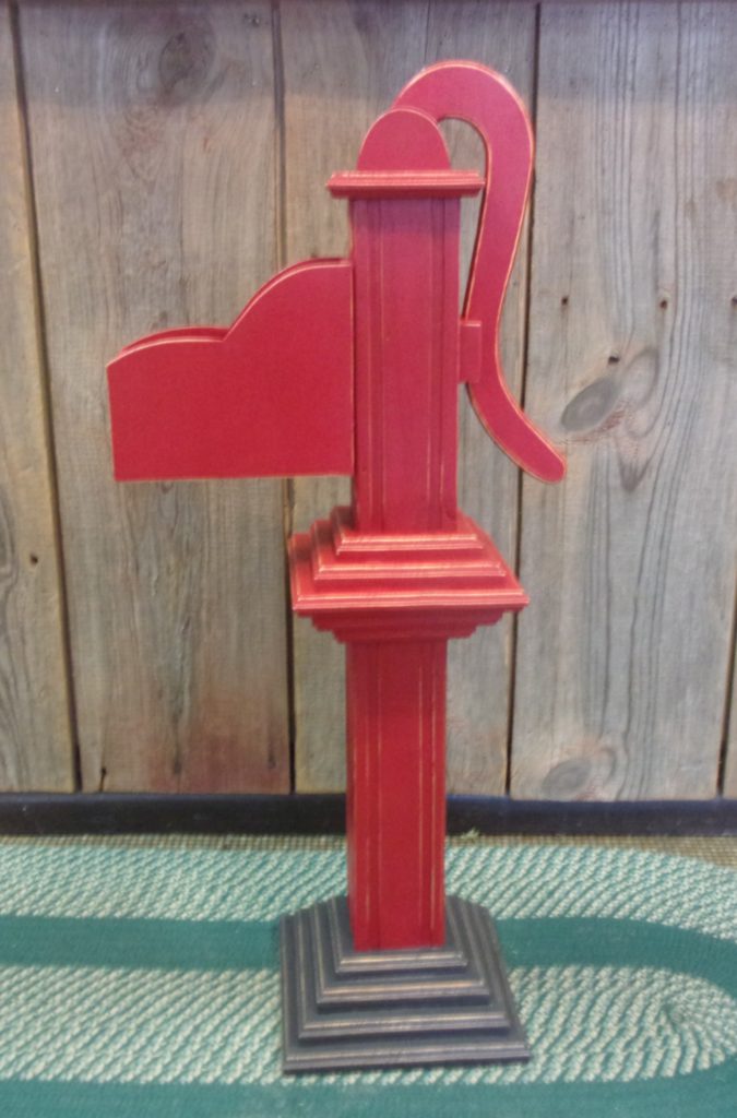  left side view of wooden hand pump painted red with gray base