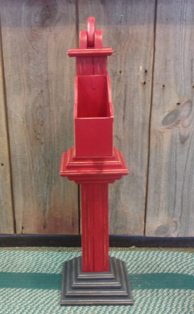 front view of wooden hand pump painted red with gray base